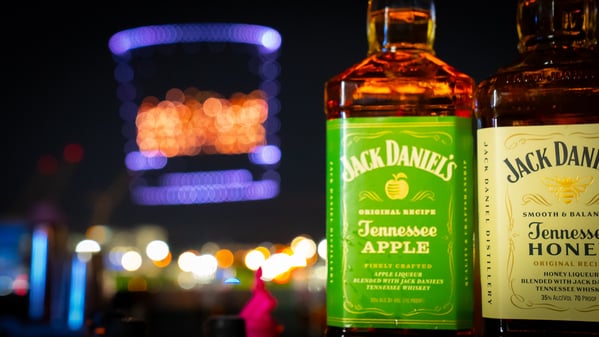 a close up image of a jack Daniels bottle with a drone show behind it