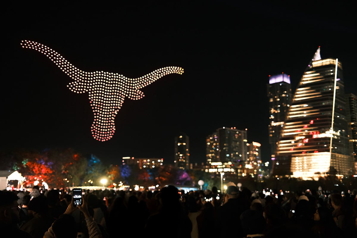 a drone light show showing the longhorn logo in downtown Austin Texas with a crowd watching during new year's eve
