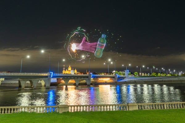 a drone show is seen where a hand reaches through a portal to grab a Mountain Dew drink