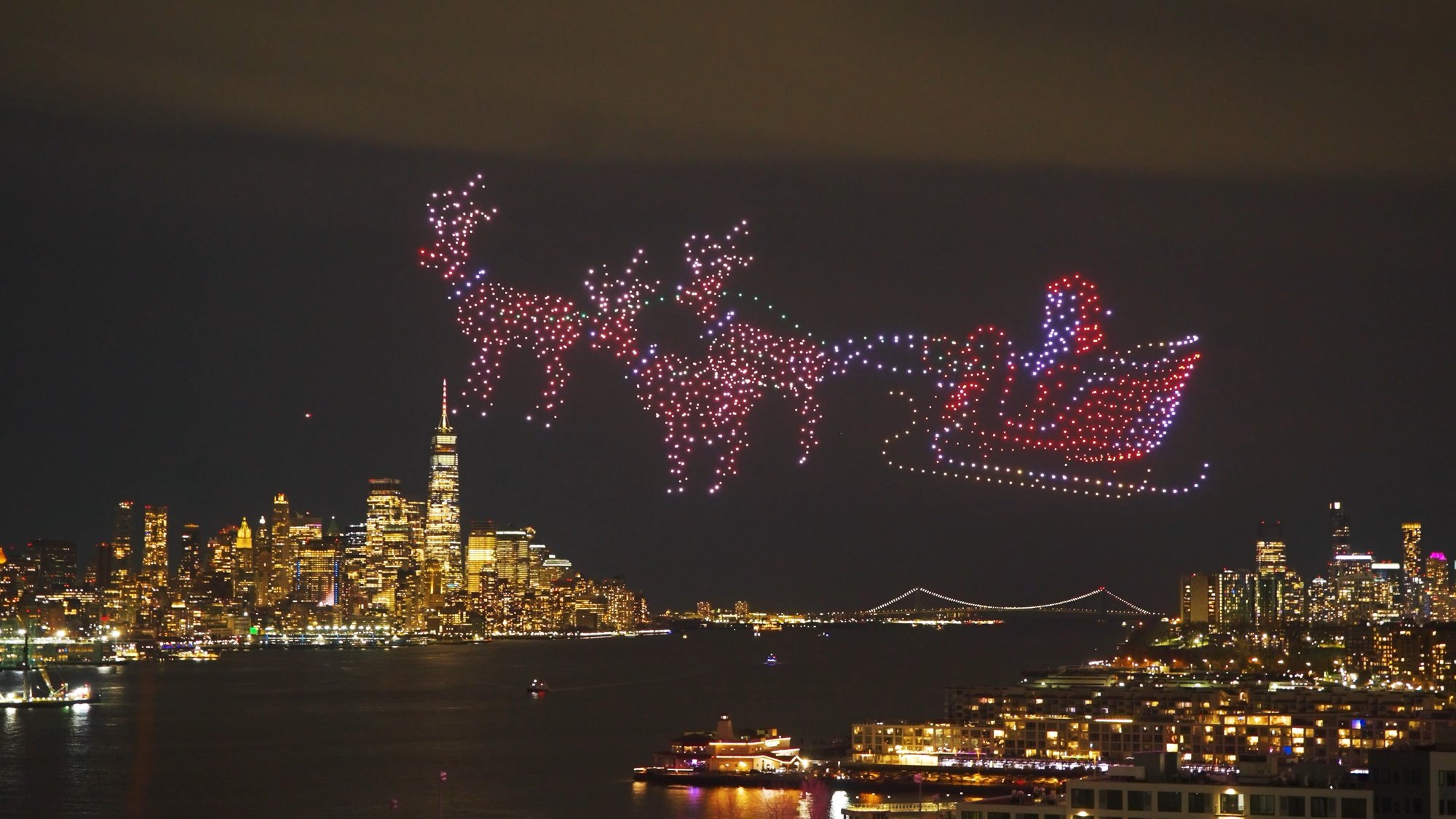A festive drone show of Santa in a sleigh pulled by reindeer over the New York City skyline.