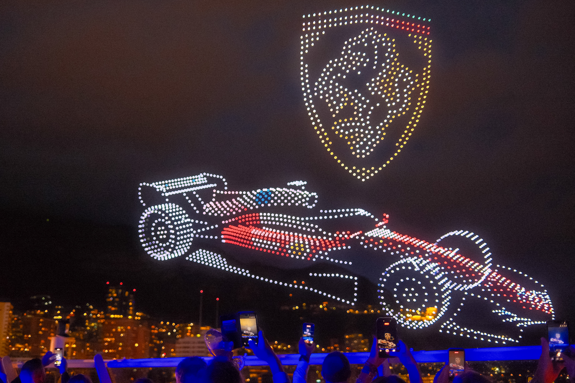 A three-dimensional Formula 1 race car and team crest drawn in drones