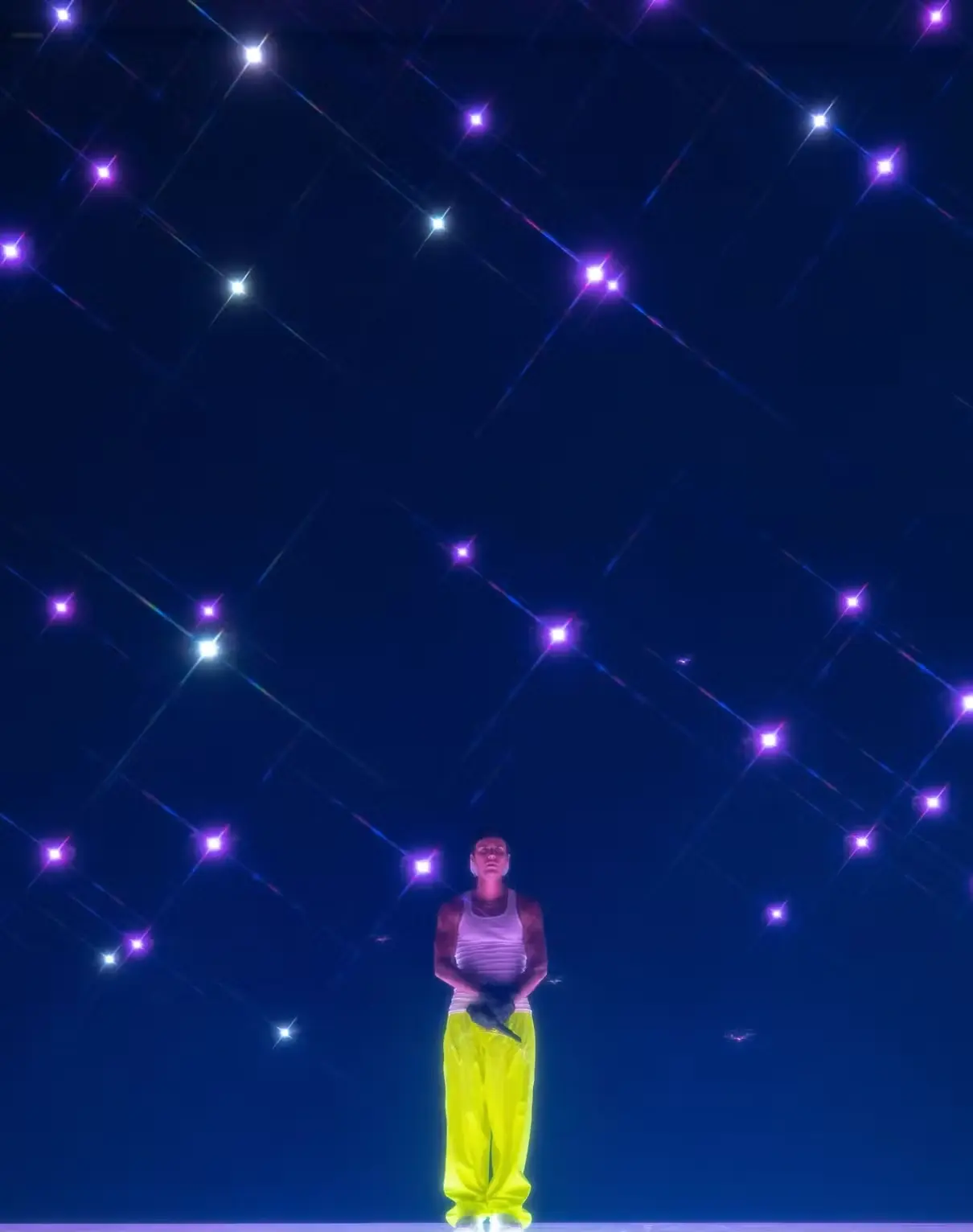 Performer standing beneath a grid of glowing drones during an indoor drone light show