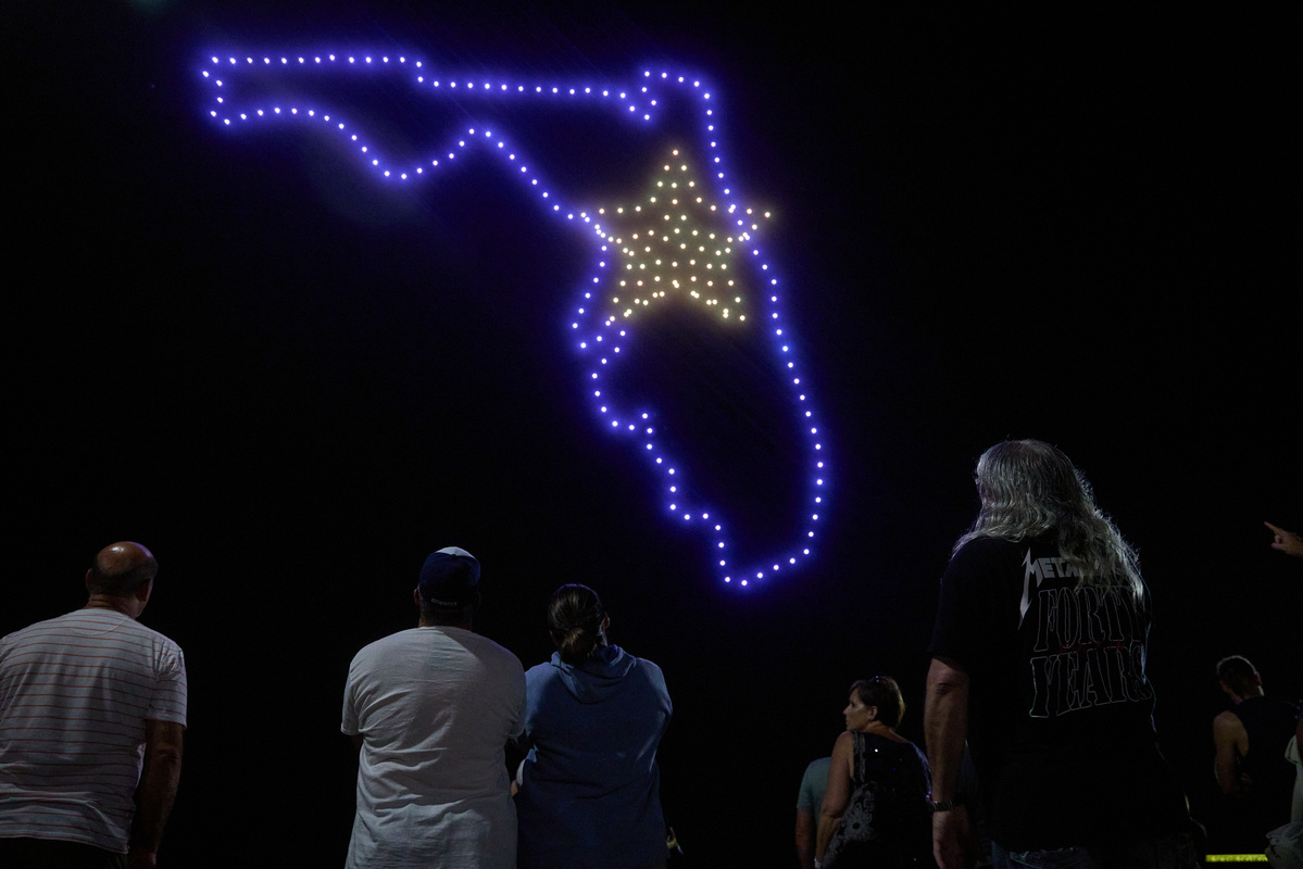 Drone show of a map of Florida with a star in the middle with people watching