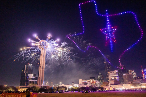 a drone show next to reunion tower in dallas Texas with the drone show showing the shape of Texas