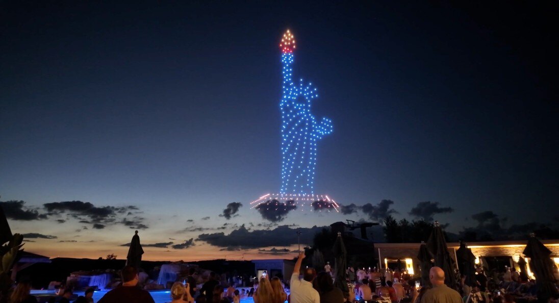 a drone show showing the Statue of Liberty as the audience looks up